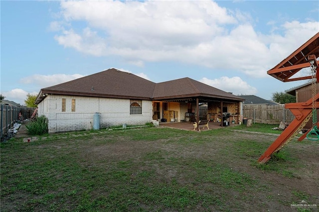 back of property featuring a patio, a playground, and a lawn