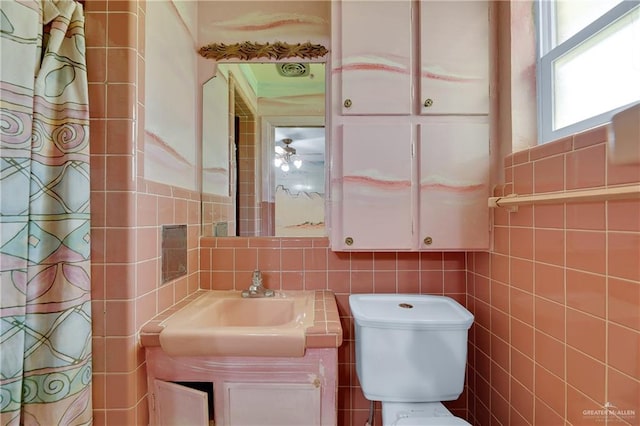 bathroom with sink, ceiling fan, toilet, and tile walls