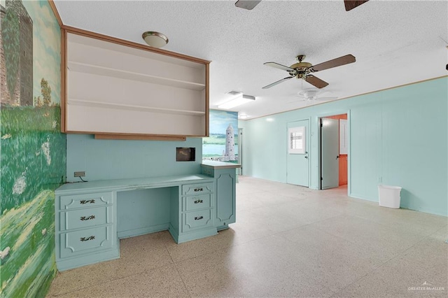 kitchen with ceiling fan, built in desk, and a textured ceiling