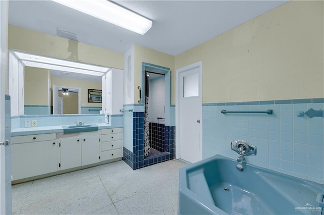 bathroom featuring vanity, a bath, tile walls, and ceiling fan