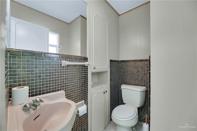 bathroom featuring toilet, sink, and tile walls