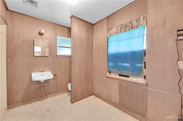 bathroom featuring toilet and wood walls