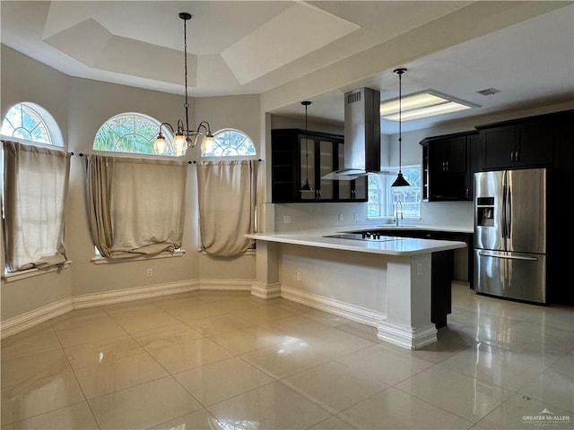 kitchen featuring island exhaust hood, pendant lighting, a tray ceiling, stainless steel fridge, and kitchen peninsula