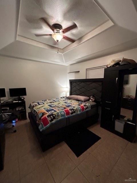 bedroom with tile patterned floors, a raised ceiling, and ceiling fan