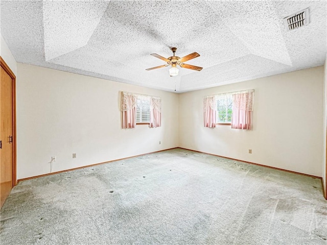 carpeted empty room featuring a textured ceiling, a tray ceiling, and ceiling fan