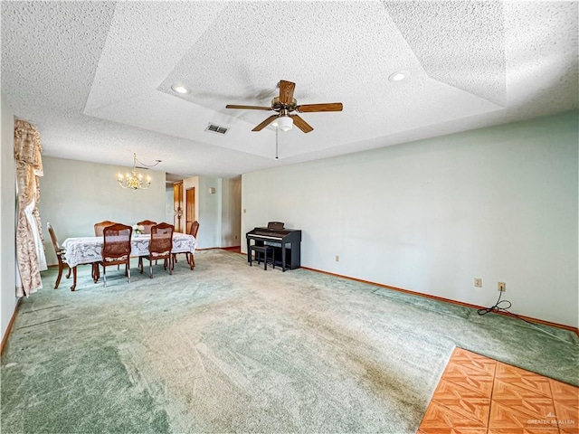 interior space with a textured ceiling, ceiling fan with notable chandelier, a tray ceiling, and carpet floors