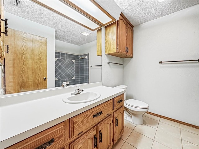 bathroom featuring tile patterned floors, vanity, a textured ceiling, tiled shower, and toilet