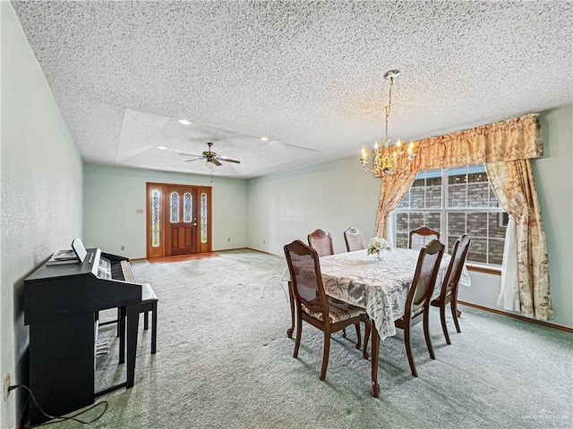 carpeted dining space featuring ceiling fan with notable chandelier, a raised ceiling, and a textured ceiling