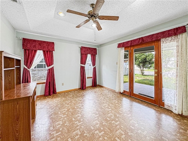 interior space featuring a textured ceiling, a tray ceiling, and ceiling fan