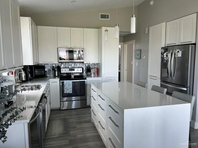 572 Sand Dollar Dr, Port Isabel, TX 78578 - kitchen with stainless steel appliances, tasteful backsplash, a center island, white cabinets, and light countertops