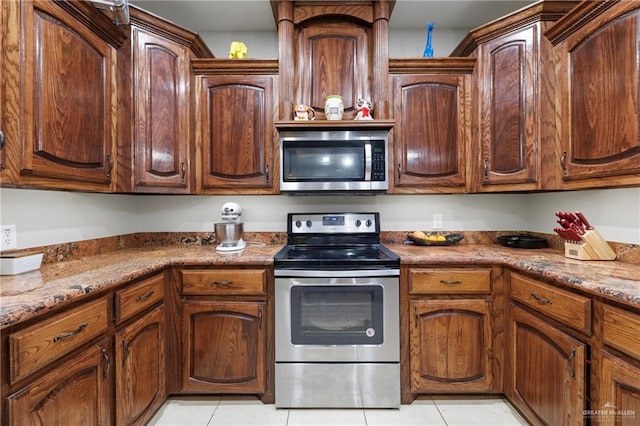 kitchen featuring stainless steel appliances, light stone counters, and light tile patterned floors