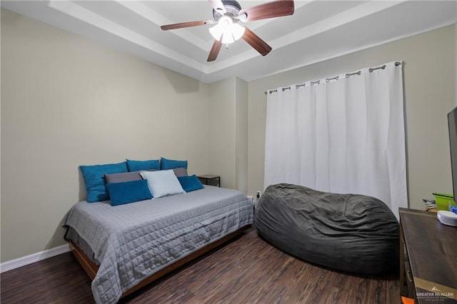 bedroom featuring ceiling fan, a raised ceiling, and dark hardwood / wood-style floors