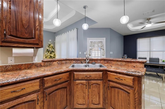 kitchen featuring light stone counters, pendant lighting, light tile patterned floors, ceiling fan, and sink