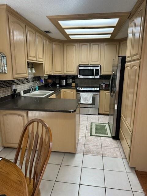 kitchen featuring sink, light tile patterned floors, kitchen peninsula, and appliances with stainless steel finishes