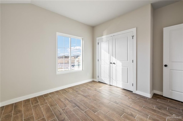 unfurnished bedroom with lofted ceiling, dark wood-type flooring, and a closet