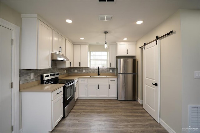 kitchen featuring white cabinets, sink, a barn door, wood-type flooring, and stainless steel appliances