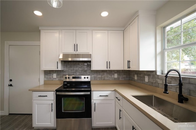 kitchen featuring stainless steel electric stove, a healthy amount of sunlight, white cabinets, and sink