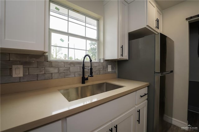 kitchen featuring dark wood-type flooring, sink, decorative backsplash, stainless steel fridge, and white cabinetry