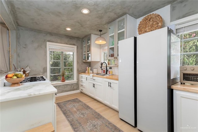 1011 W Orange St, Mcallen, TX 78501 - kitchen with freestanding refrigerator, glass insert cabinets, light wood finished floors, white cabinets, and recessed lighting