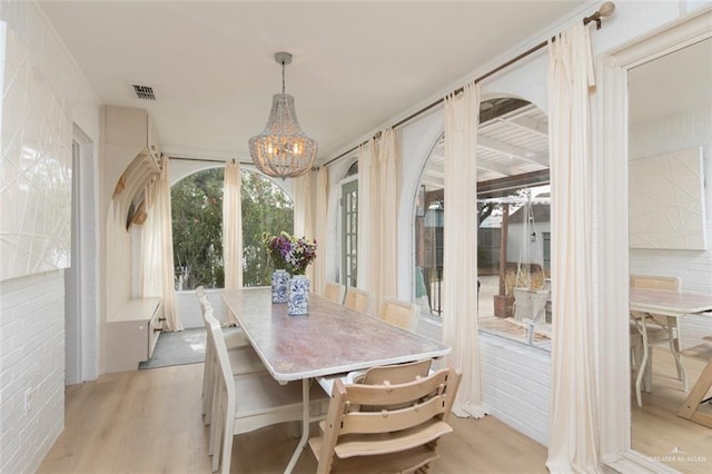 1011 W Orange St, Mcallen, TX 78501 - dining space featuring a chandelier, light wood-type flooring, and brick wall