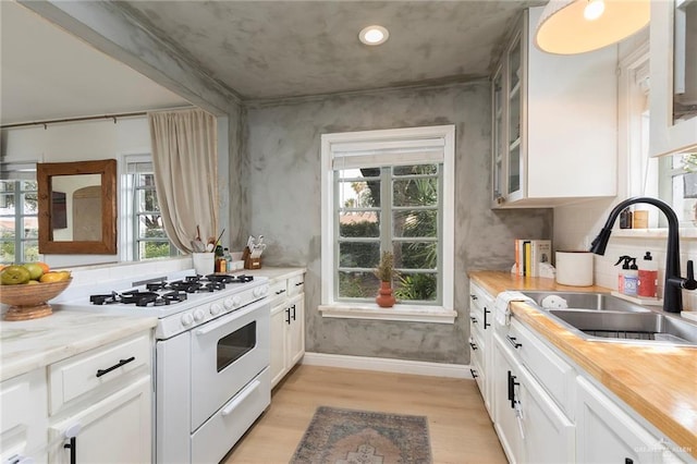 1011 W Orange St, Mcallen, TX 78501 - kitchen featuring white gas range oven, light wood finished floors, white cabinets, glass insert cabinets, and wooden counters