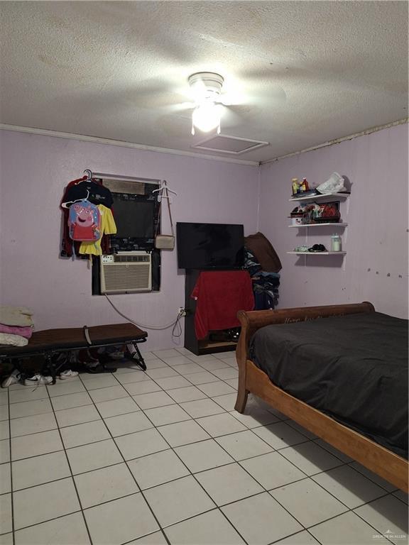 bedroom featuring light tile patterned floors, a textured ceiling, ceiling fan, and cooling unit