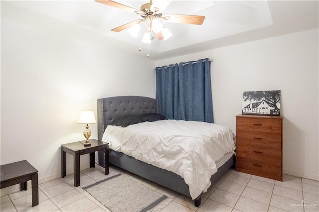 tiled bedroom with ceiling fan and a raised ceiling