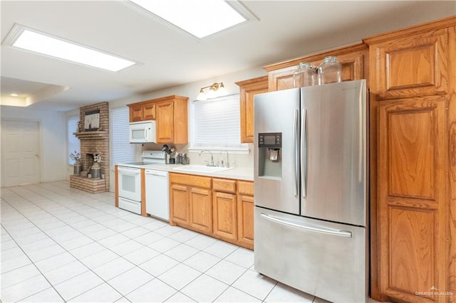 kitchen with light tile patterned flooring, sink, a fireplace, and white appliances