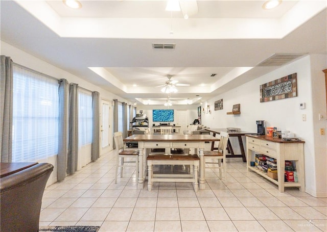 dining room with ceiling fan, light tile patterned flooring, and a tray ceiling