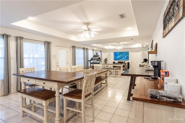 tiled dining area featuring ceiling fan and a raised ceiling