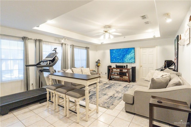 tiled living room featuring ceiling fan and a tray ceiling