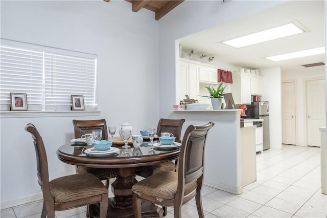 dining space with light tile patterned floors and lofted ceiling with beams