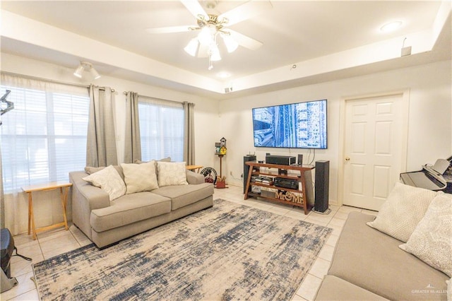 tiled living room featuring ceiling fan and a tray ceiling