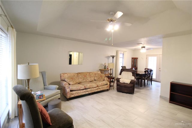 living room with a tray ceiling and ceiling fan