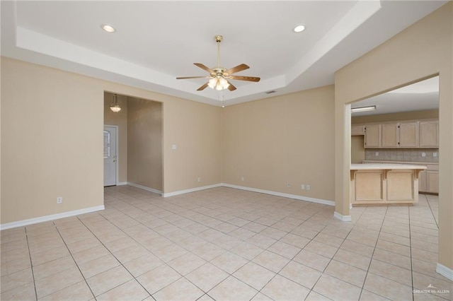 spare room featuring ceiling fan, a raised ceiling, and light tile patterned floors