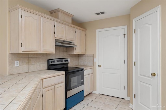 kitchen featuring backsplash, electric stove, tile counters, and light tile patterned floors