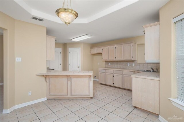 kitchen with sink, tile countertops, kitchen peninsula, decorative backsplash, and light tile patterned flooring