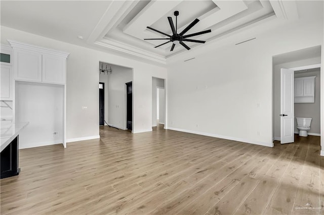 unfurnished living room featuring a raised ceiling, ceiling fan, and light hardwood / wood-style floors