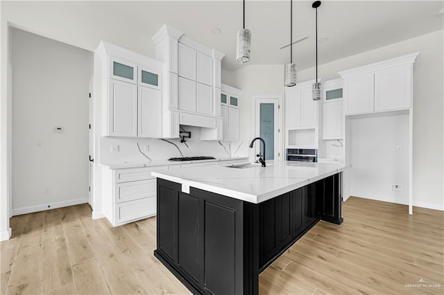 kitchen featuring pendant lighting, sink, white cabinetry, wall oven, and a large island with sink