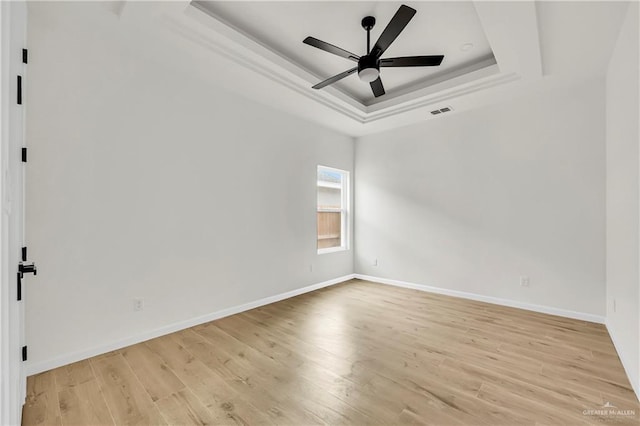 unfurnished room with ceiling fan, a raised ceiling, and light hardwood / wood-style floors