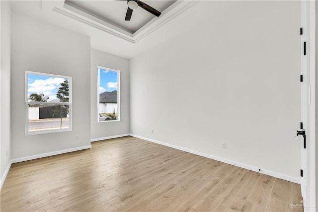 spare room with a tray ceiling, light hardwood / wood-style floors, and ceiling fan