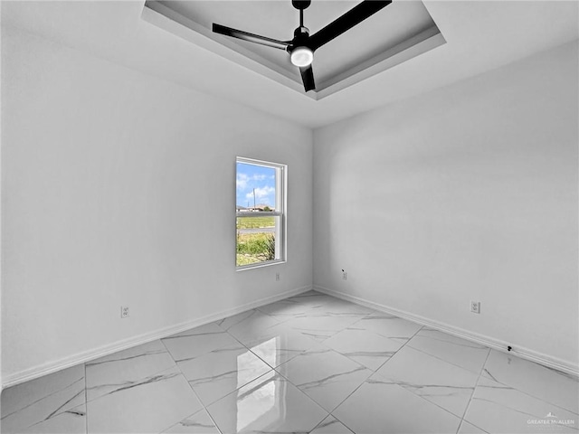 spare room featuring a raised ceiling and ceiling fan