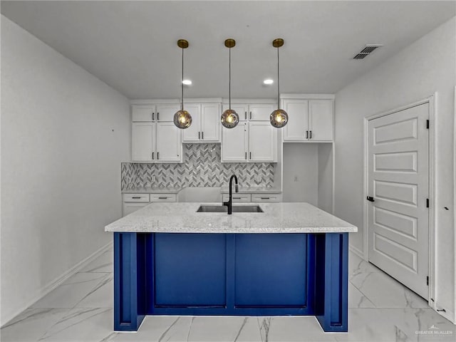 kitchen with sink, tasteful backsplash, decorative light fixtures, a kitchen island with sink, and white cabinets