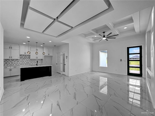 unfurnished living room featuring beamed ceiling, ceiling fan, coffered ceiling, and sink