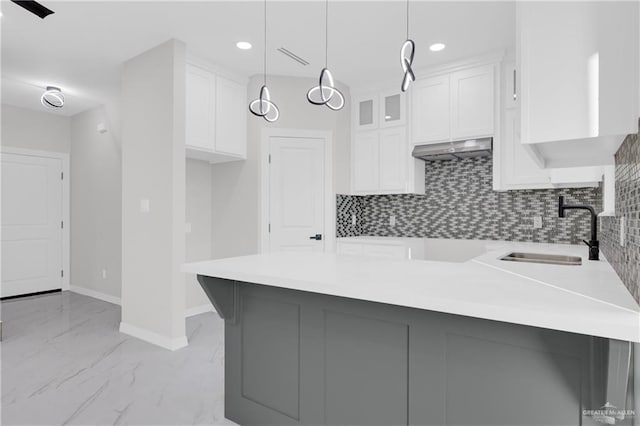 kitchen with pendant lighting, sink, backsplash, white cabinets, and kitchen peninsula