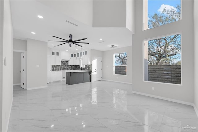 unfurnished living room with a high ceiling and ceiling fan