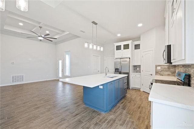 2214 N Gaytan St, Edinburg, TX 78542 - kitchen with stainless steel appliances, a sink, blue cabinets, ceiling fan, and decorative backsplash