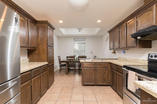 kitchen with a sink, light tile patterned floors, appliances with stainless steel finishes, a peninsula, and under cabinet range hood