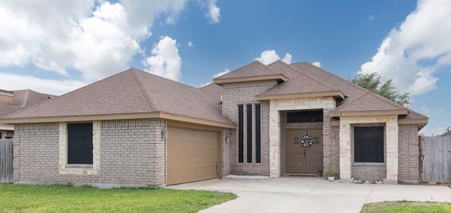 view of front of property featuring roof with shingles, driveway, fence, a garage, and brick siding
