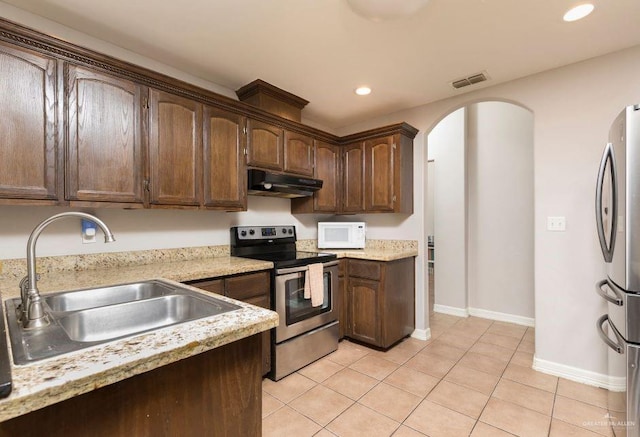 kitchen with arched walkways, a sink, recessed lighting, under cabinet range hood, and appliances with stainless steel finishes